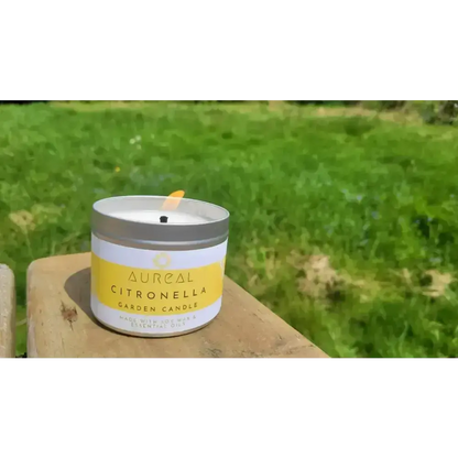 Lit Aureal Citronella garden candle on a wooden bench in a garden