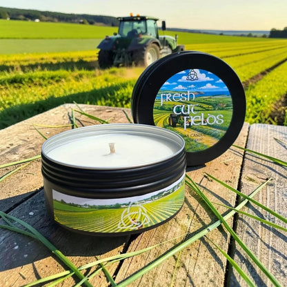 Fresh Cut Fields tin candle on a wooden table with a tractor in a field behind