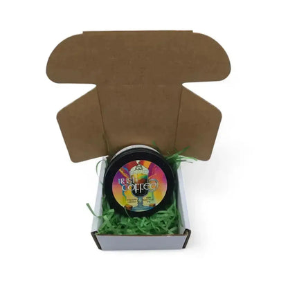 Irish Coffee candle tin in an open brown mailer box with green paper shred
