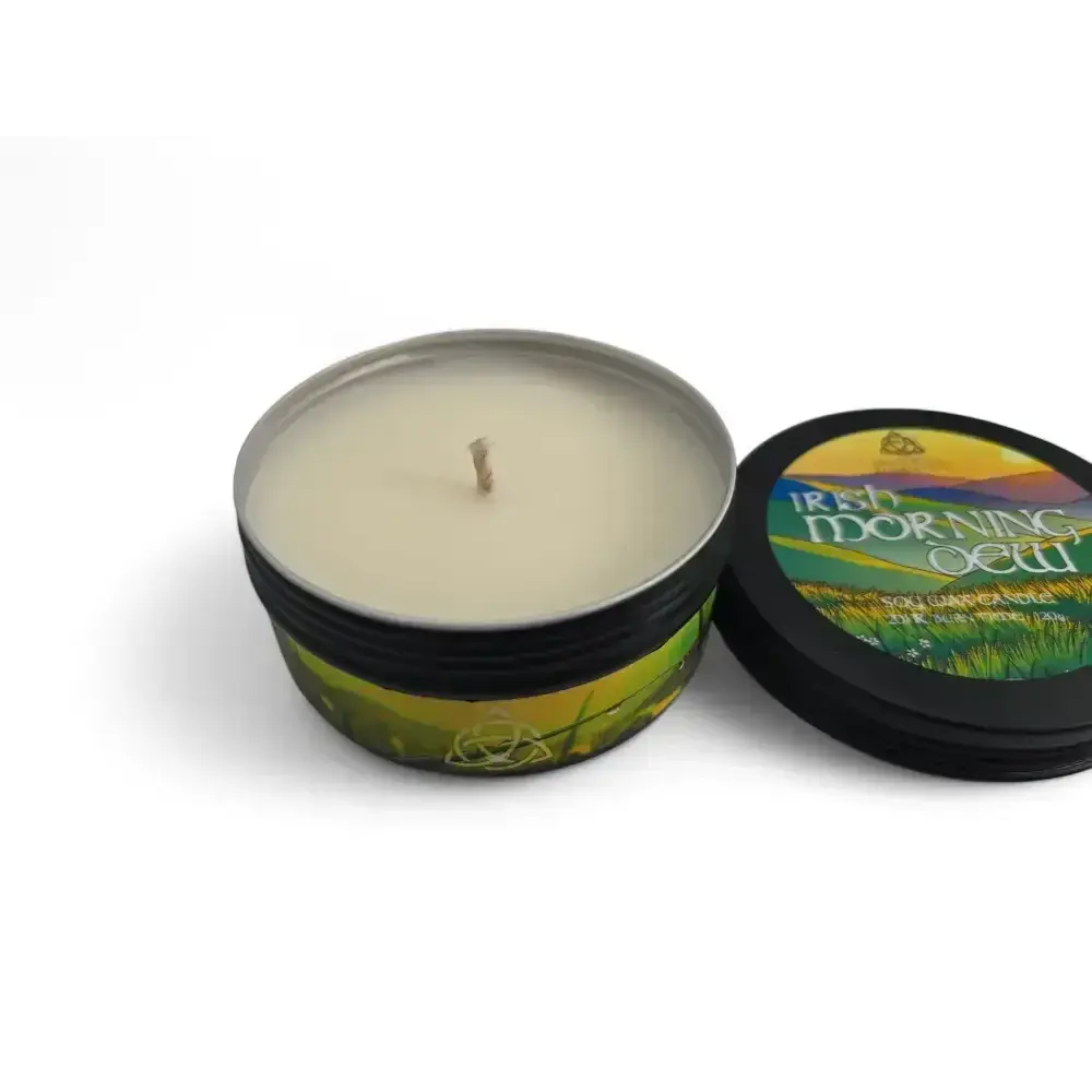 Irish Morning Dew candle in a black tin with its lid propped beside it