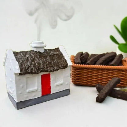 White cottage burner with smoke rising, beside a small brown basket of turf sods
