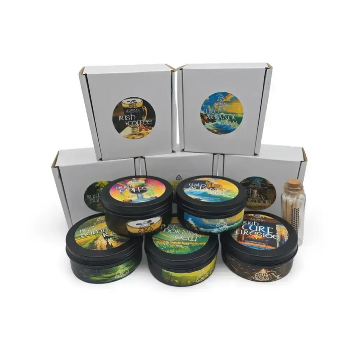 Five black candle tins with colourful lids in front of their white boxes, with a bottle of matches