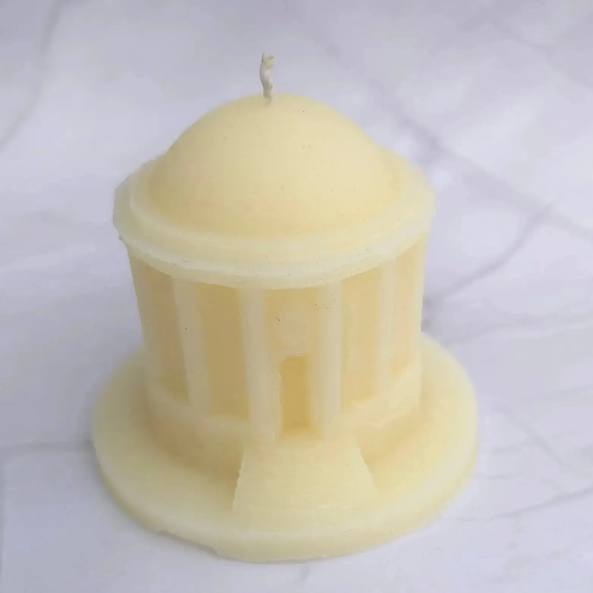 Cream beeswax Mussenden Temple candle from the front, showing the columns and doorway